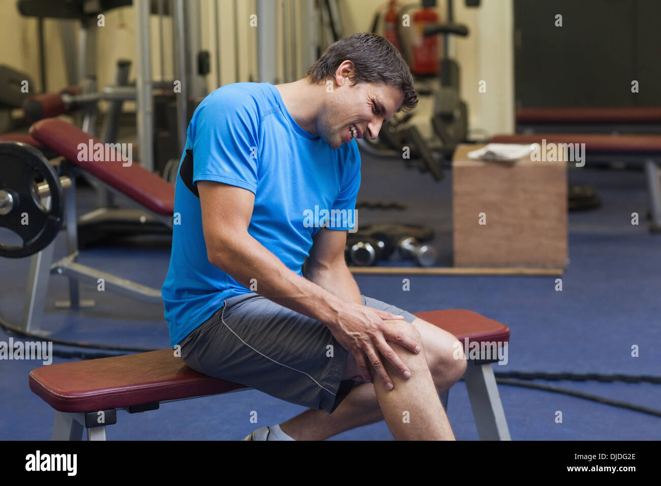 Gesunde Menschen mit einem verletzten Bein sitzen im Fitness-Studio Stockfoto