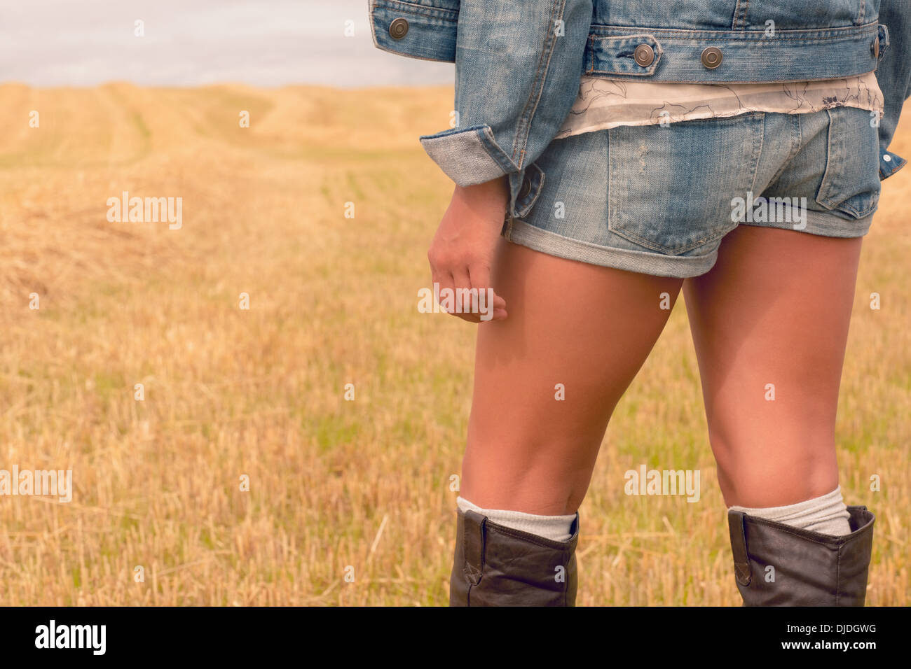 Mittleren Bereich der Frau in Jeans-Shorts und Stiefeln auf Getreide-Feld Stockfoto