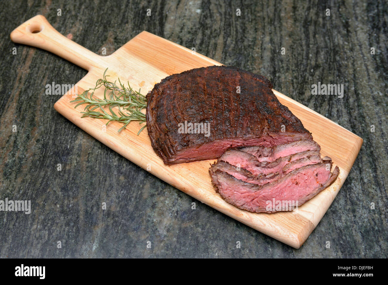 Gegrilltes Wagyu Rock Steak und Rosmarin auf Schneidebrett. © Craig M. Eisenberg Stockfoto