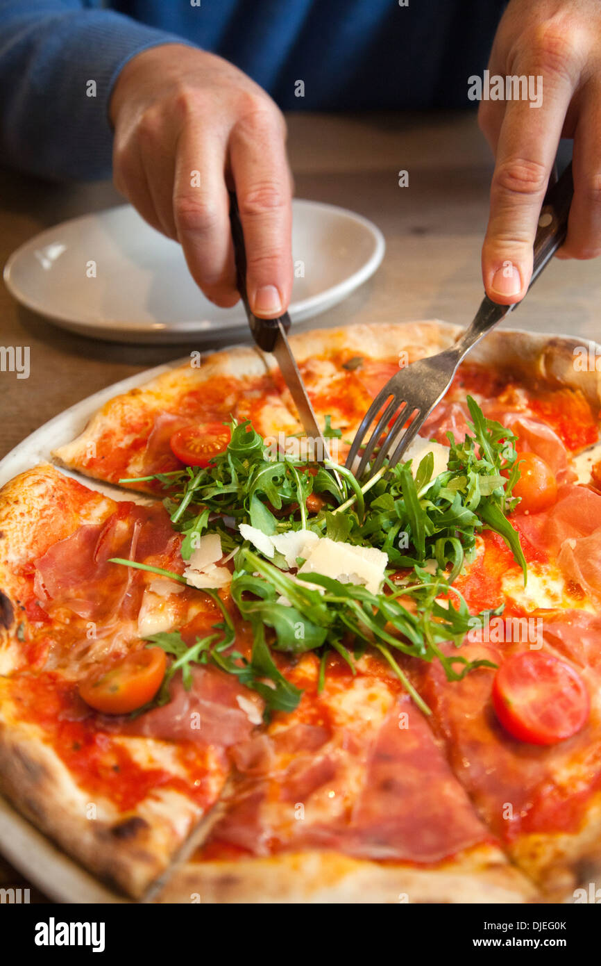 Mann unter Stück San Daniele Pizza mit Rucola und Prosciutto Stockfoto