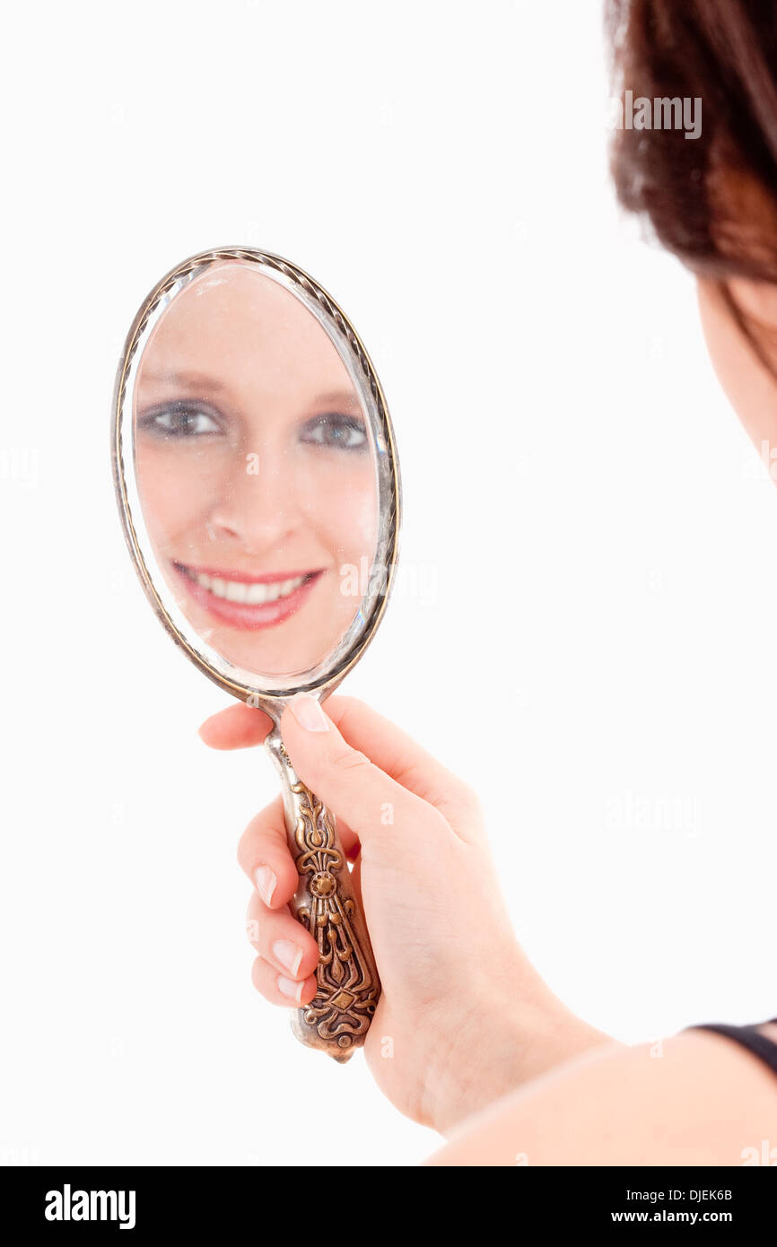 Junge Frau mit Blick auf ihr Spiegelbild in alte Spiegel - Isolated on White Stockfoto
