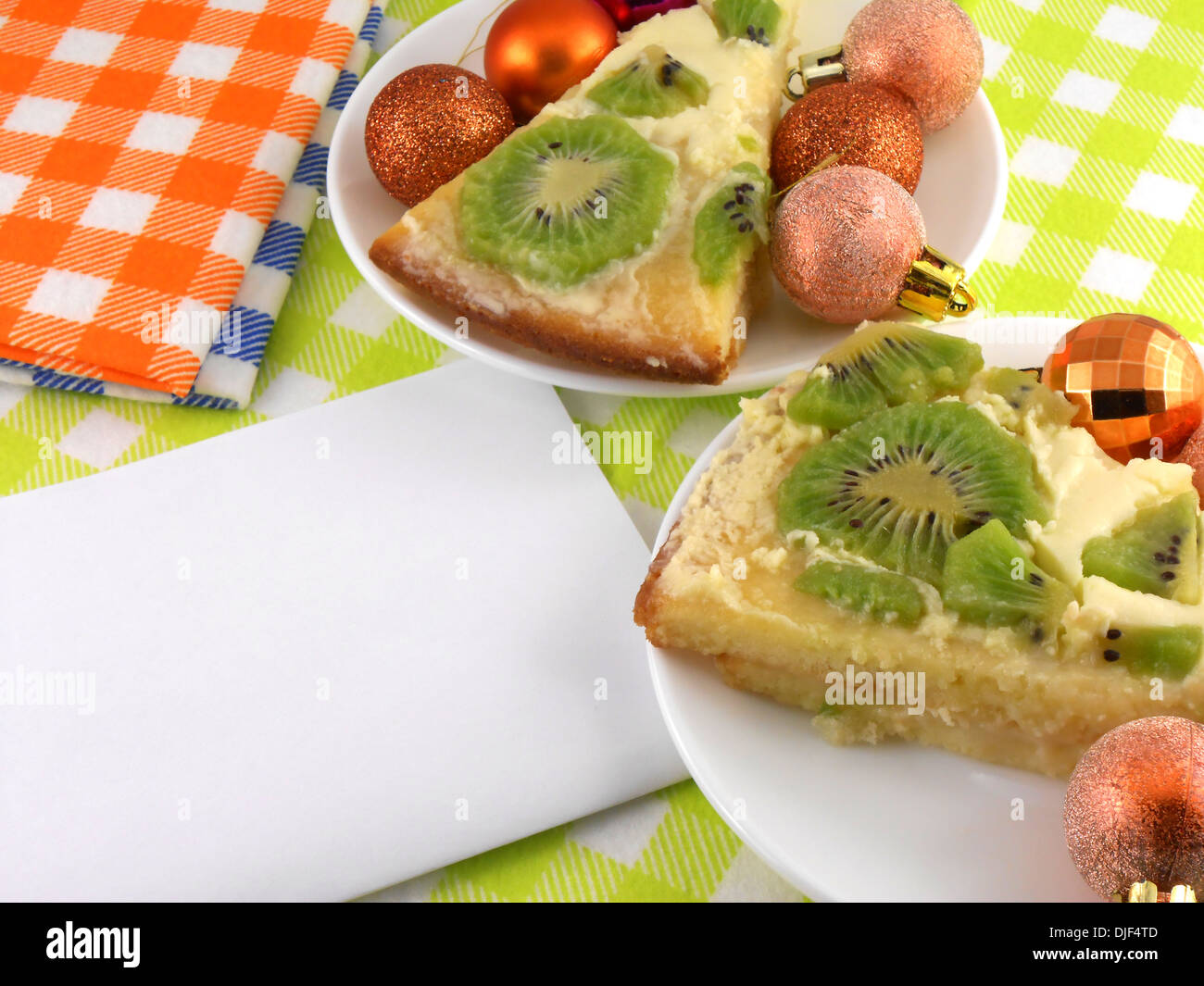 Kiwi Kuchen auf Teller mit weißen leeres Papier und Weihnachten Kugeln set Stockfoto