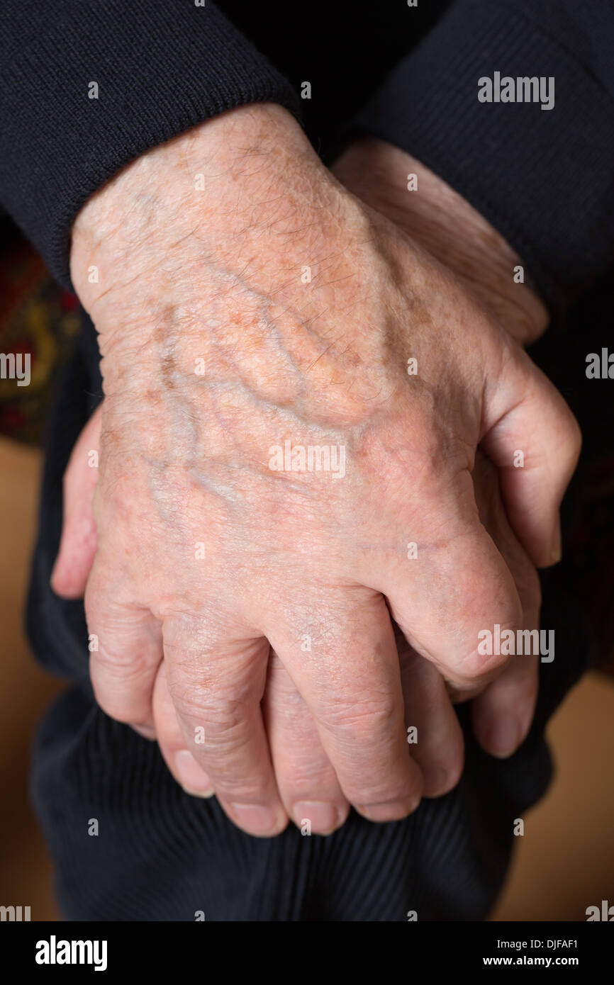 Ein alte Alter Mensch hält seine Hände über seinem Knie gekreuzt Stockfoto
