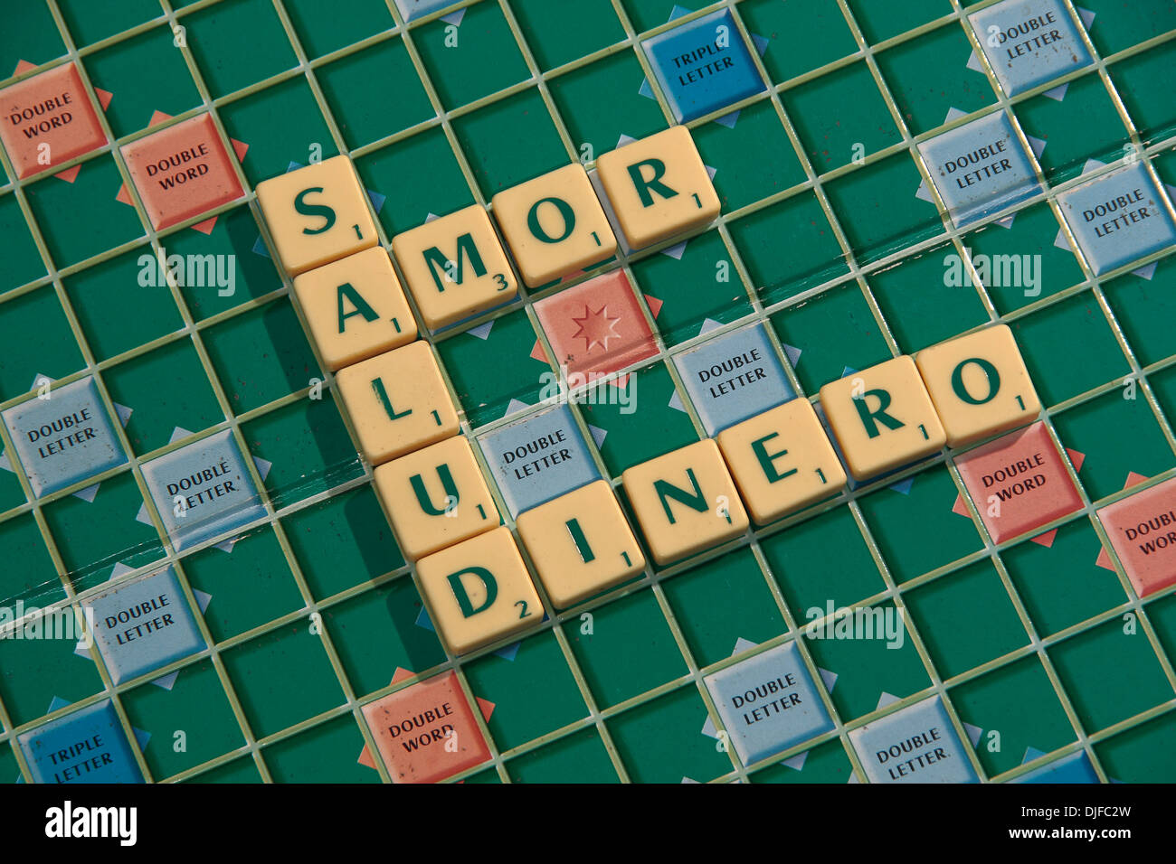 Die spanische Phrase, "Salud Amor y Dinero" (Gesundheit, Liebe und Geld) in Scrabble Fliesen auf einem Scrabble-Brett geschrieben. Stockfoto