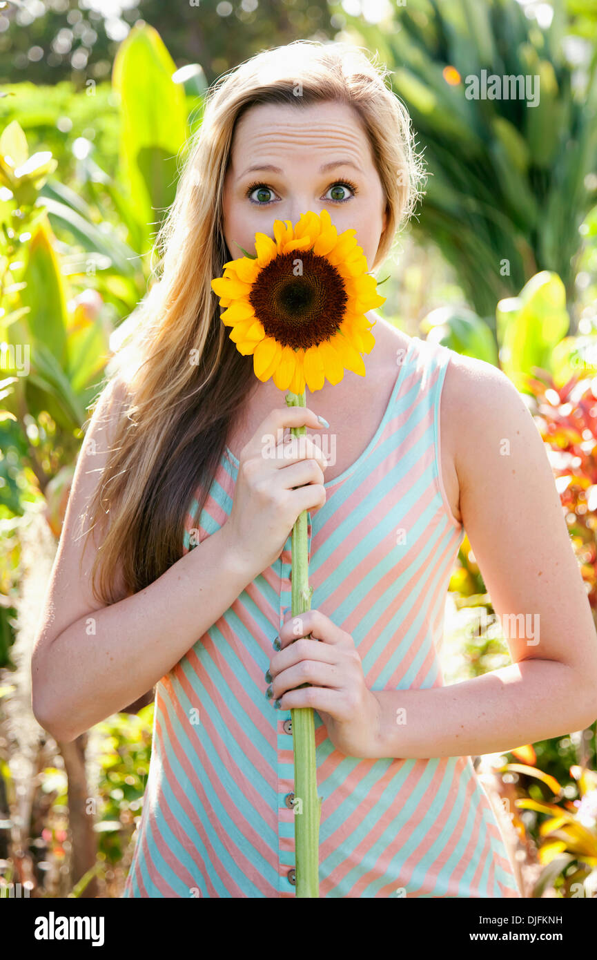 Porträt eines Mädchens, die Augen weit mit einer Sonnenblume vor den Mund; Honolulu, Oahu, Hawaii, Vereinigte Staaten von Amerika Stockfoto
