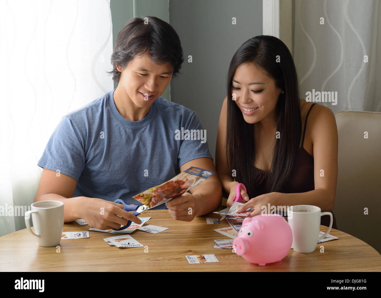 Eine junge asiatische paar schneiden Coupons, die versuchen, Geld zu sparen, genügsam und sparsam. Stockfoto