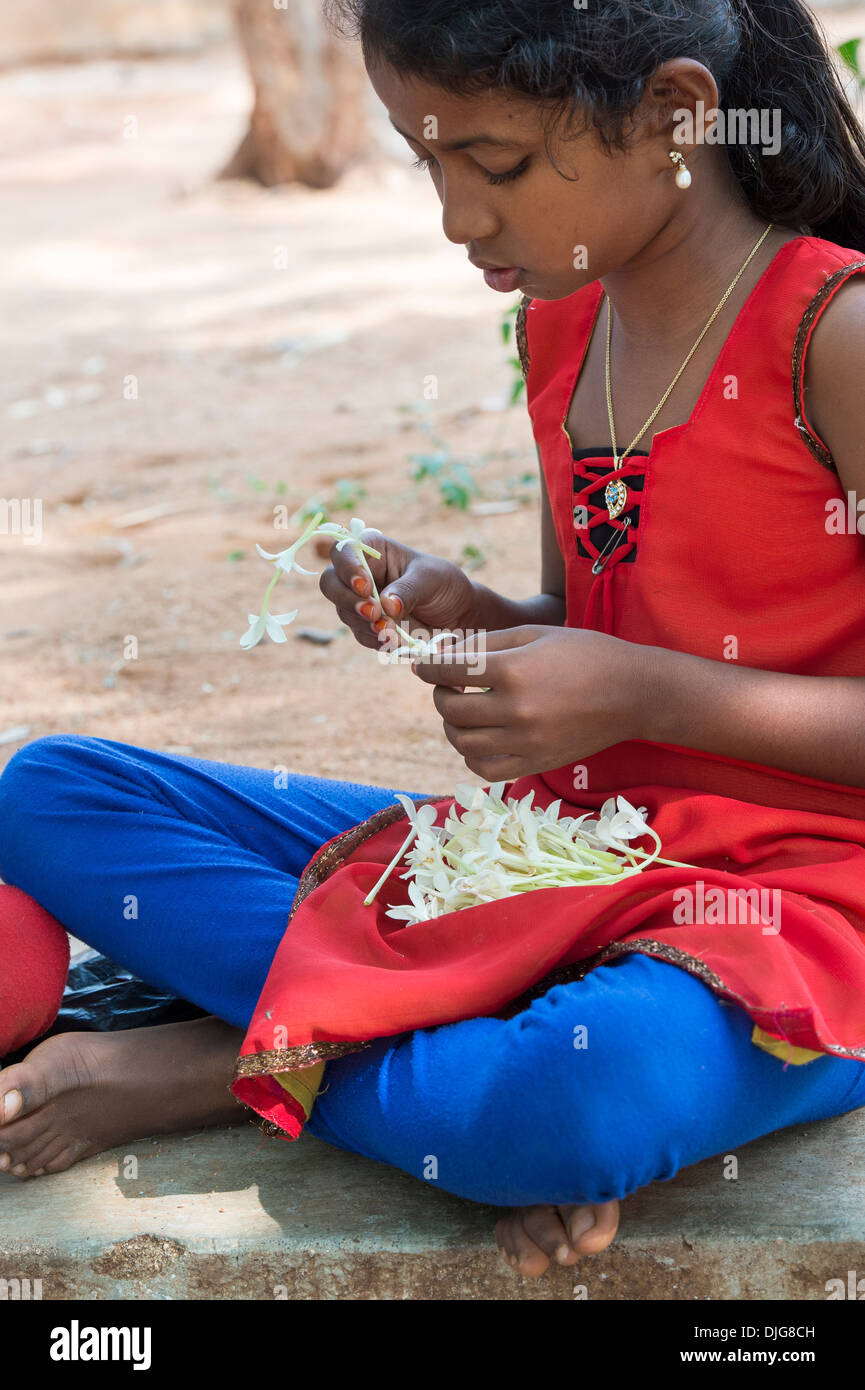 Indische Mädchen saß, eine Kette aus indischen Kork Baum Blumen. Andhra Pradesh, Indien Stockfoto