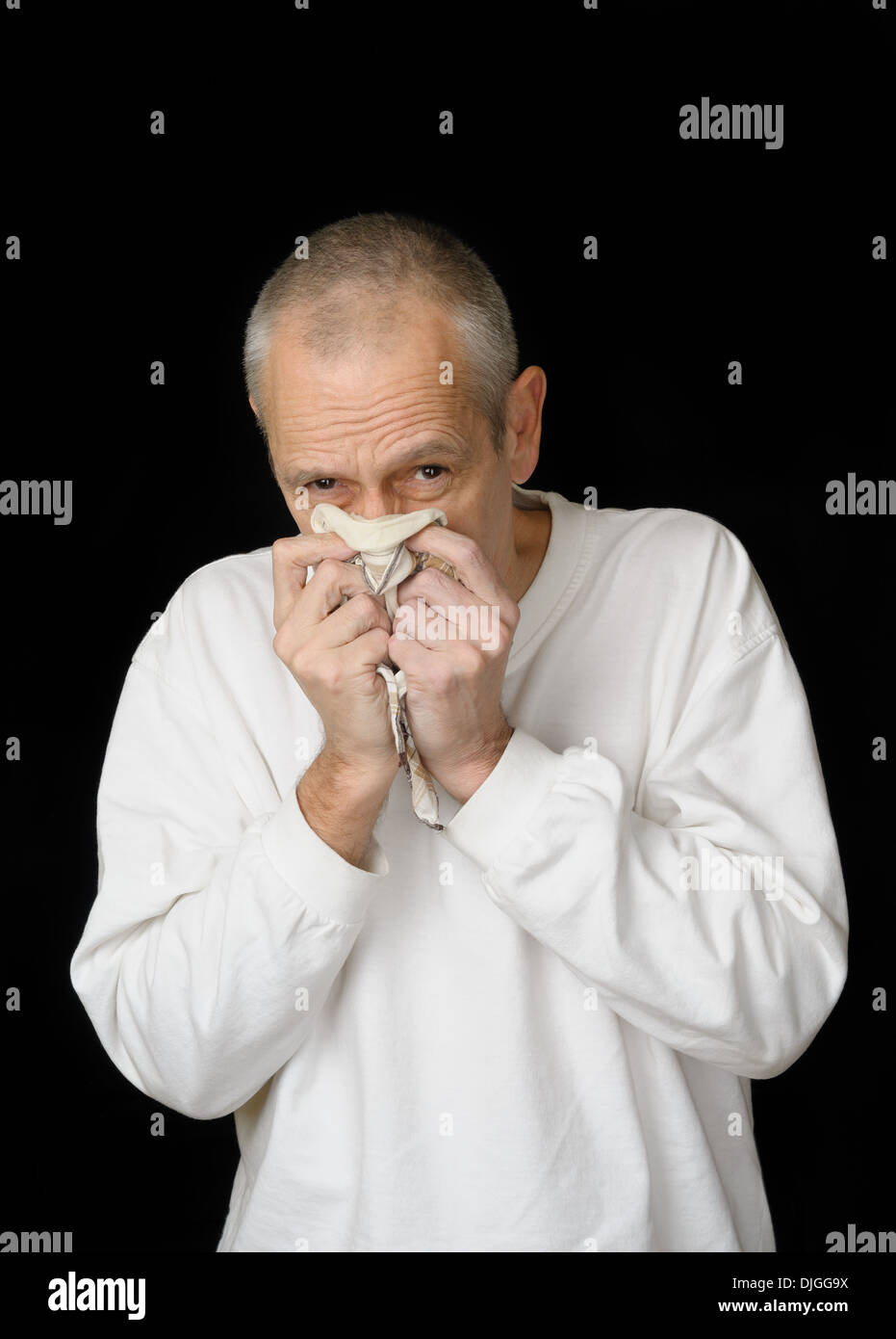 Ein kranker Mann mit kalten ein Taschentuch in den Händen halten und seine Nase weht Stockfoto