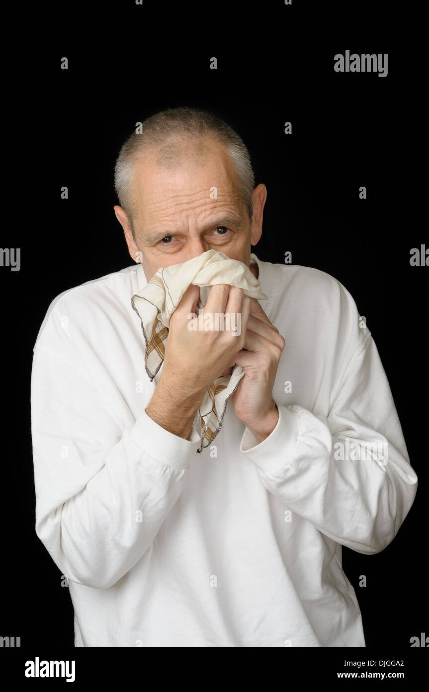 Ein kranker Mann mit kalten ein Taschentuch in den Händen halten und seine Nase weht Stockfoto