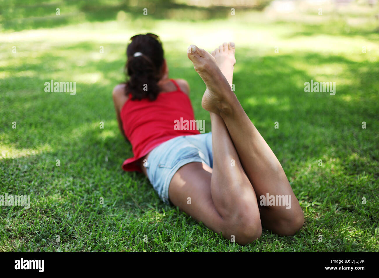 Junge Frau liegt auf dem grünen Rasen im Park. Stockfoto