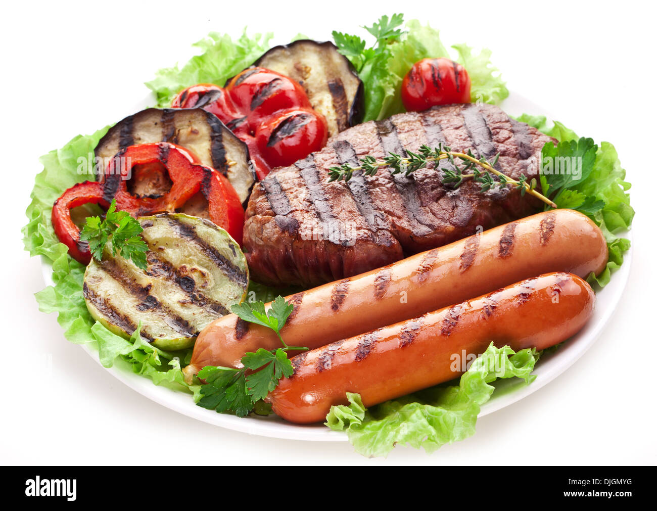 Gegrilltes Steak, Wurst und Gemüse über Salatblätter. Stockfoto