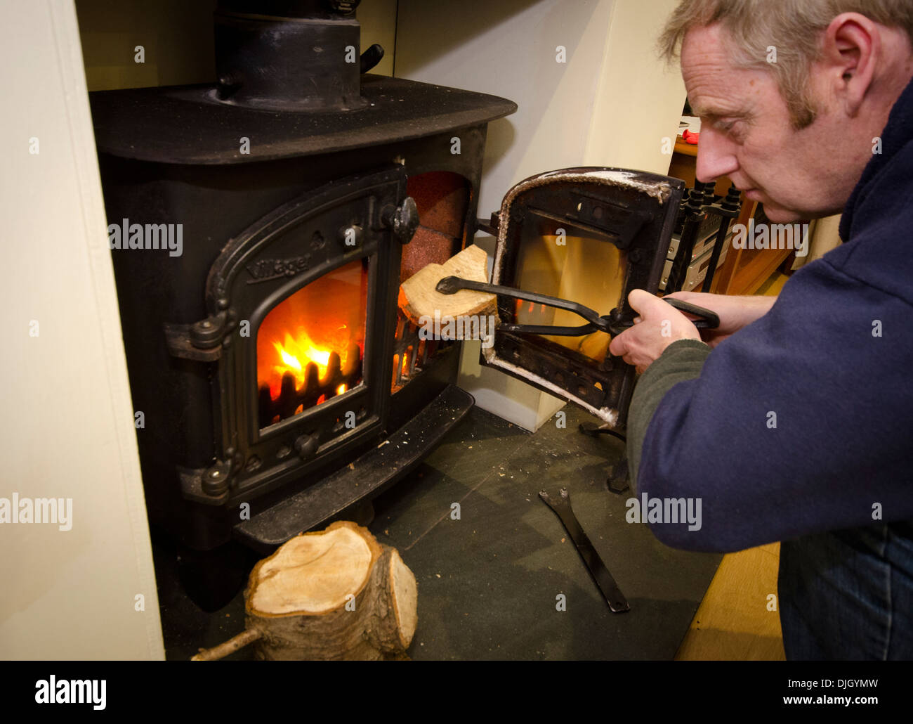 Mann, der ein Protokoll auf einem Holzofen Stockfoto