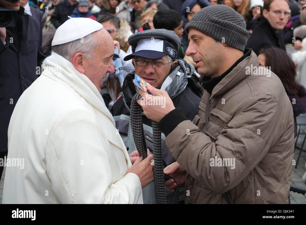 Vatikan, Rom, Italien. 27. November 2013. Papst Francis, während einem wirklich kalten Tag in St. Peter Square, ändern seinen Schal mit einer Kranken Person und seine Helfer in der Generalaudienz vom 27. November 2013 Credit: wirklich Easy Star/Alamy Live News Stockfoto