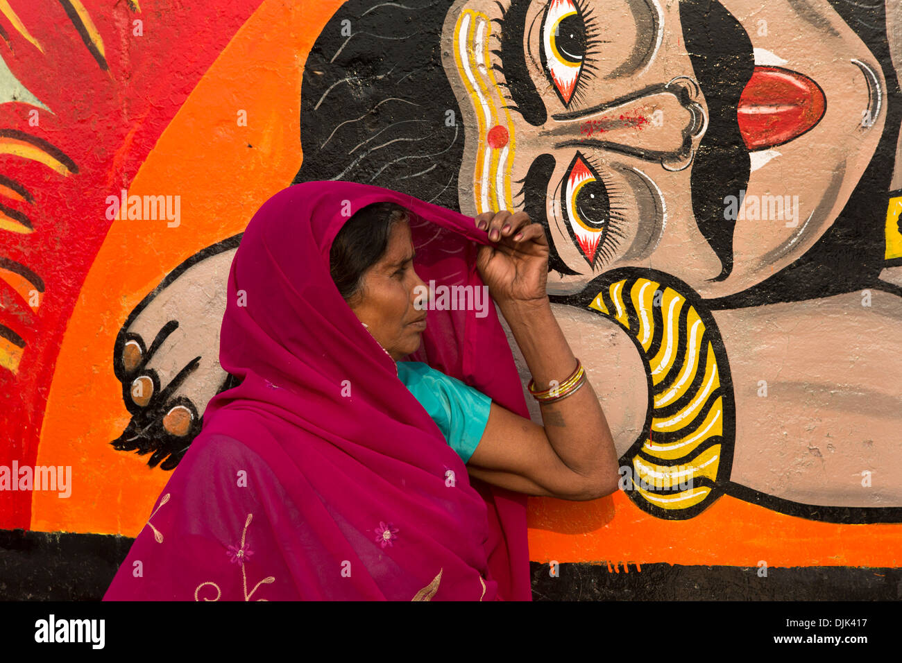 Eine Frau wartet ist eine Zeichnung repräsentieren einige der Götter der hinduistischen Religion auf einer Wand, auf dem es ruht Stockfoto