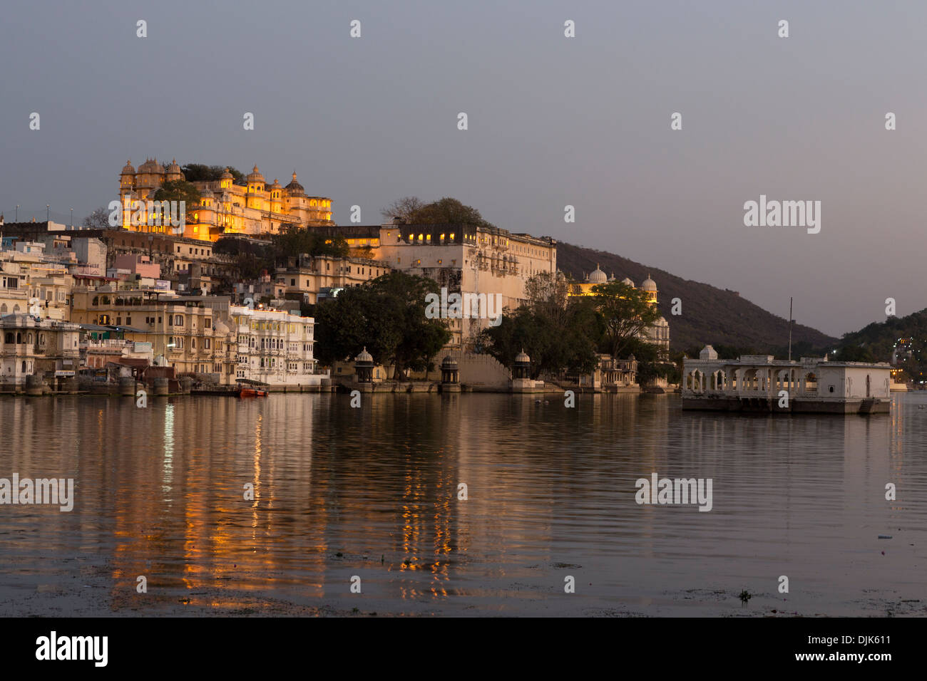 Blick auf die Stadt Udaipur am Abend mit Pichola-See und das Schloss beleuchtet Hintergrund Stockfoto