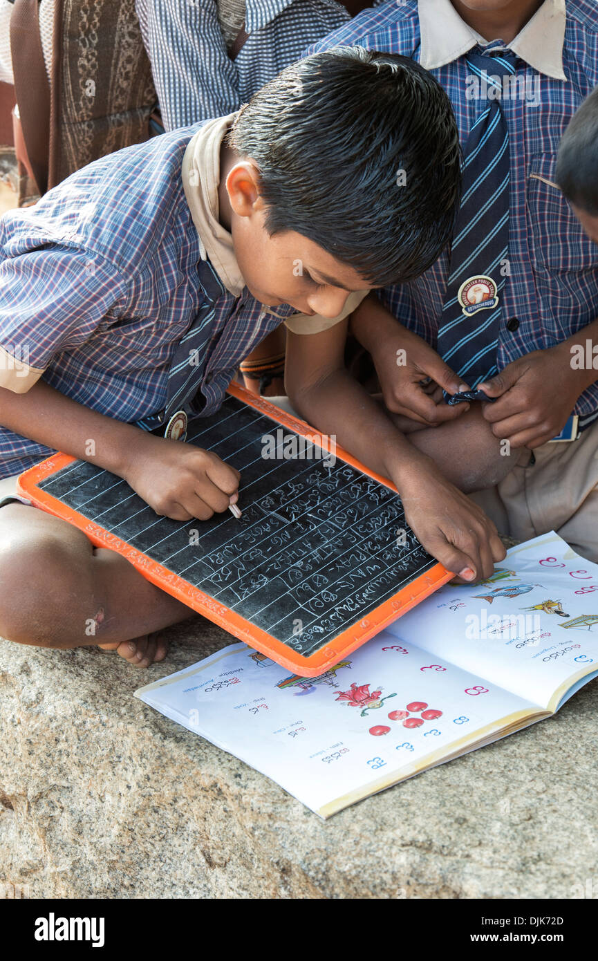 Indische Bauerndorf Schuljungen Telegu auf einem Kreide-Tablet in einer externen Klasse schreiben. Andhra Pradesh, Indien Stockfoto