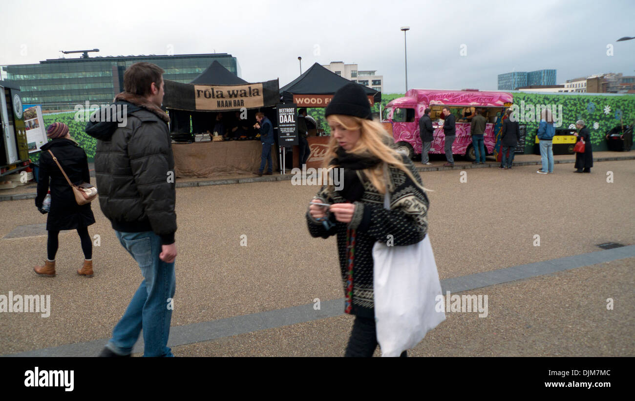 Junge Frau SMS bei einem Spaziergang vorbei an Suppen vans in Kings Cross, London UK KATHY DEWITT Stockfoto