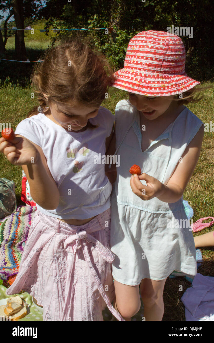 Zwei junge Mädchen Lachen und Spaß, auf ein Picknick in der Sonne, Erdbeeren halten und Spaß in Somerset, Großbritannien. Stockfoto