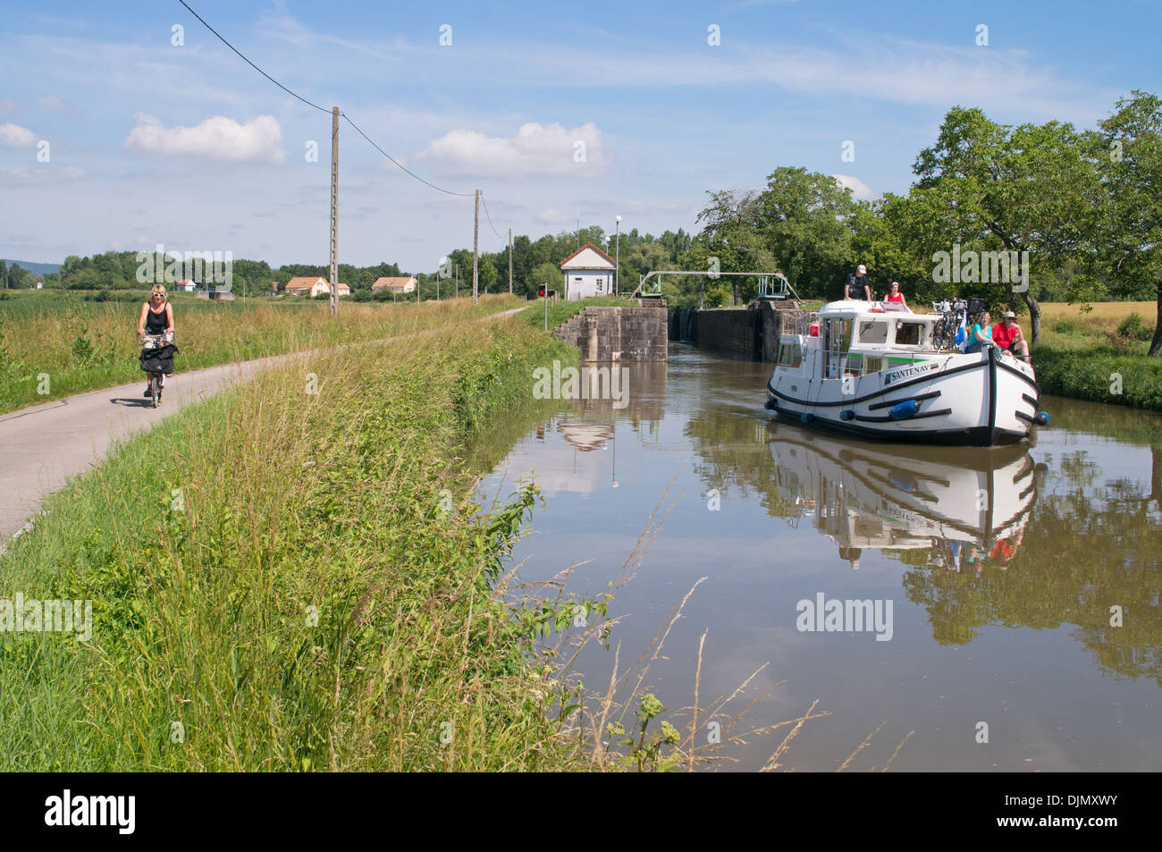 Weibliche Radfahrer fährt mit Leinpfad während Segel für nichtgewerbliche Schifffahrt entlang des Canal du Centre gleich hinter Schloss Burgund Ost-Frankreich Stockfoto