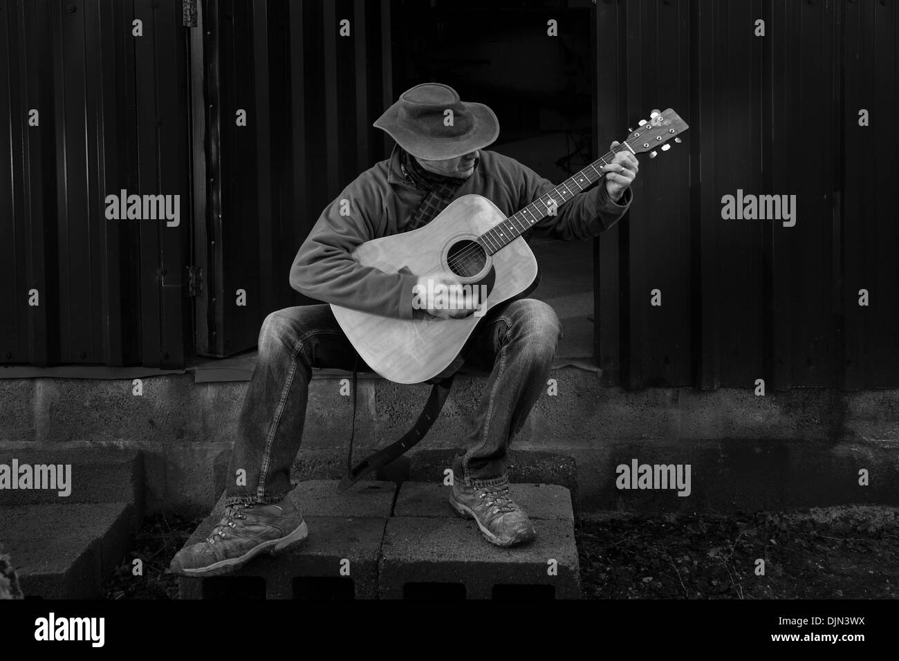 Schwarz / weiß Bild eines Mannes im Freien eine akustische Gitarre zu spielen. Stockfoto