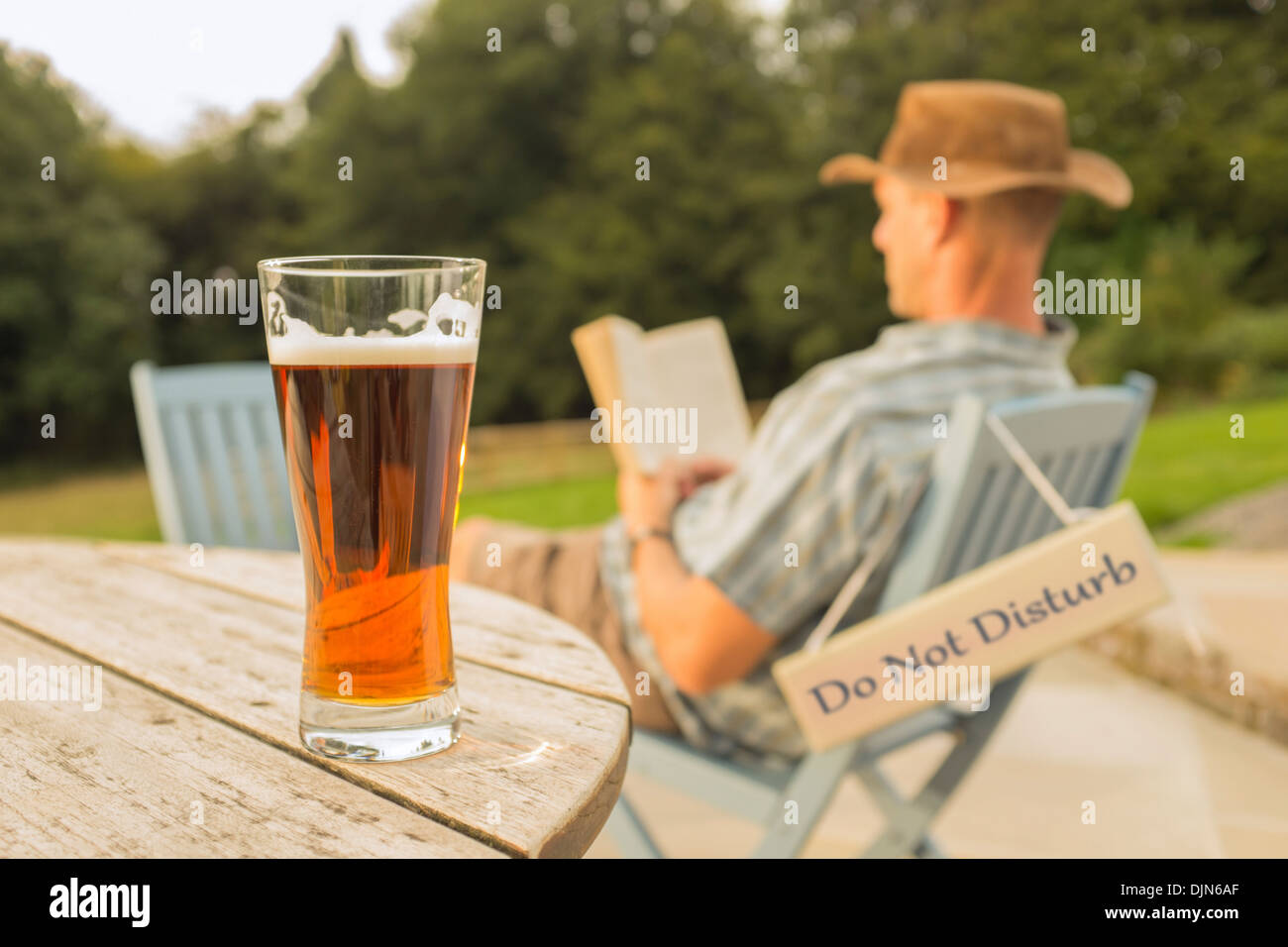 Ein Mann mit einem Buch und Glas Bier entspannen. Stockfoto