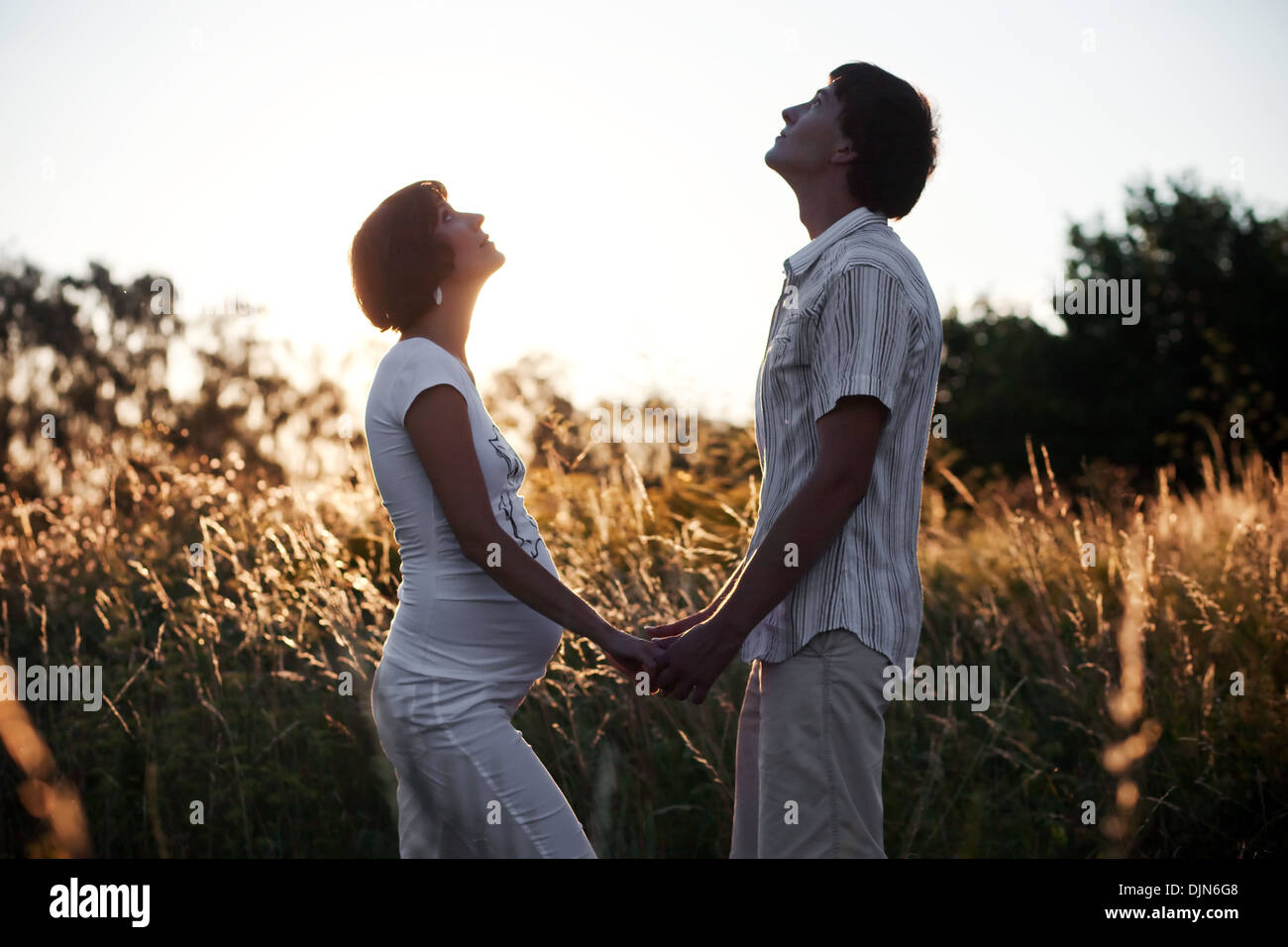 Schwangere Frau mit Mann nachschlagen am Himmel über Sonnenuntergang Stockfoto