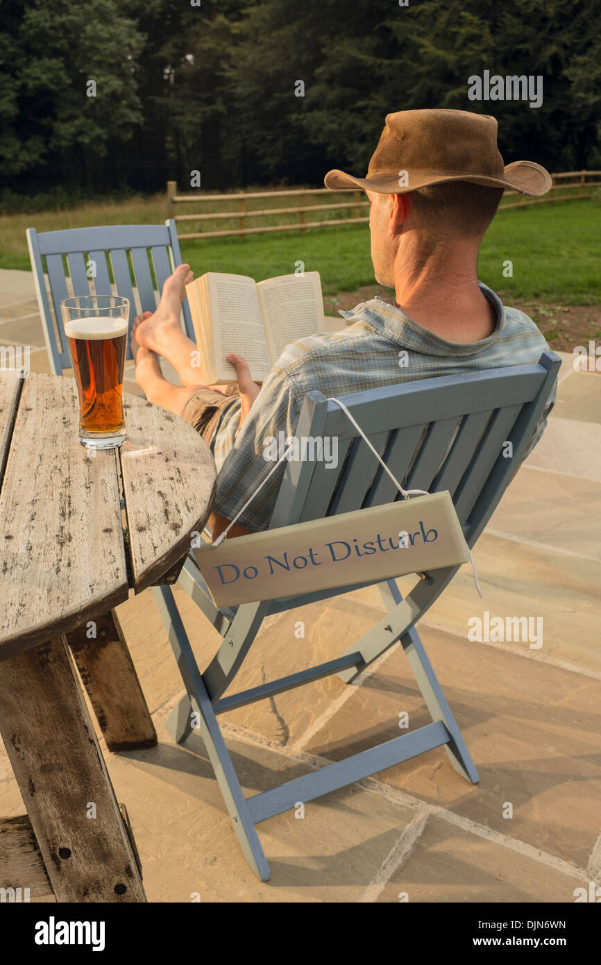 Ein Mann mit einem Buch und Glas Bier entspannen. Stockfoto