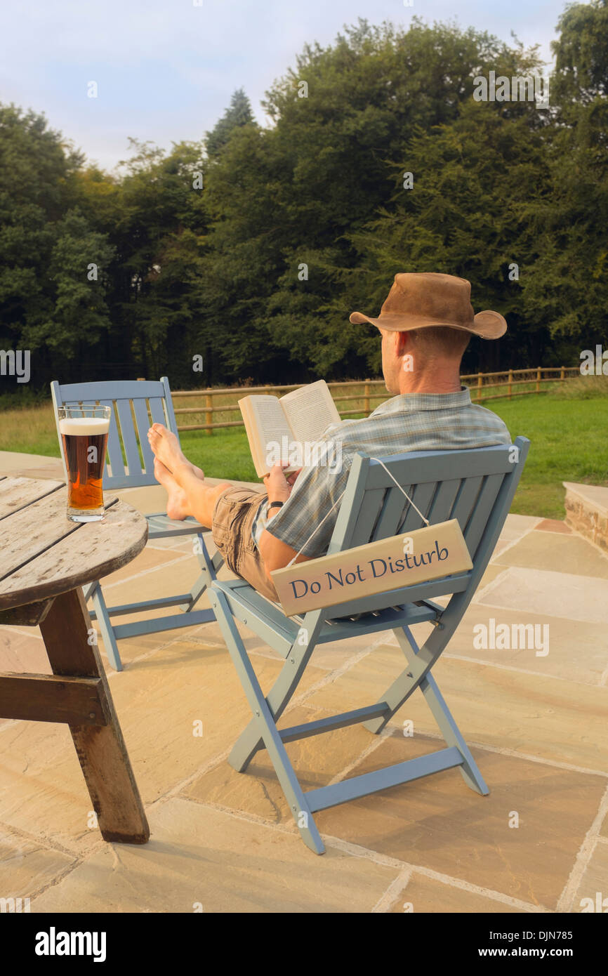 Ein Mann mit einem Buch und Glas Bier entspannen. Stockfoto