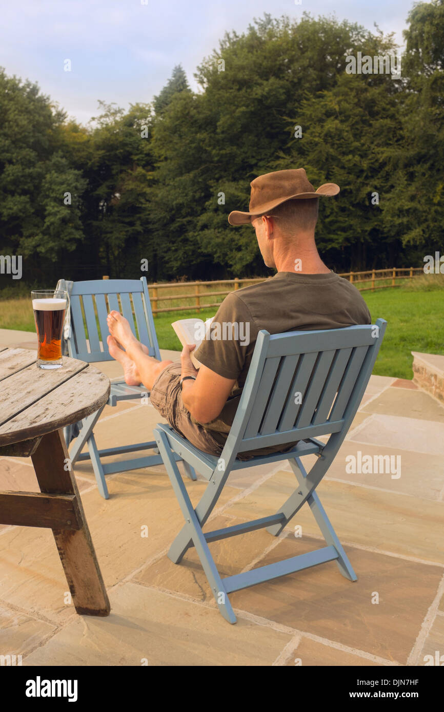 Ein Mann mit einem Buch und Glas Bier entspannen. Stockfoto