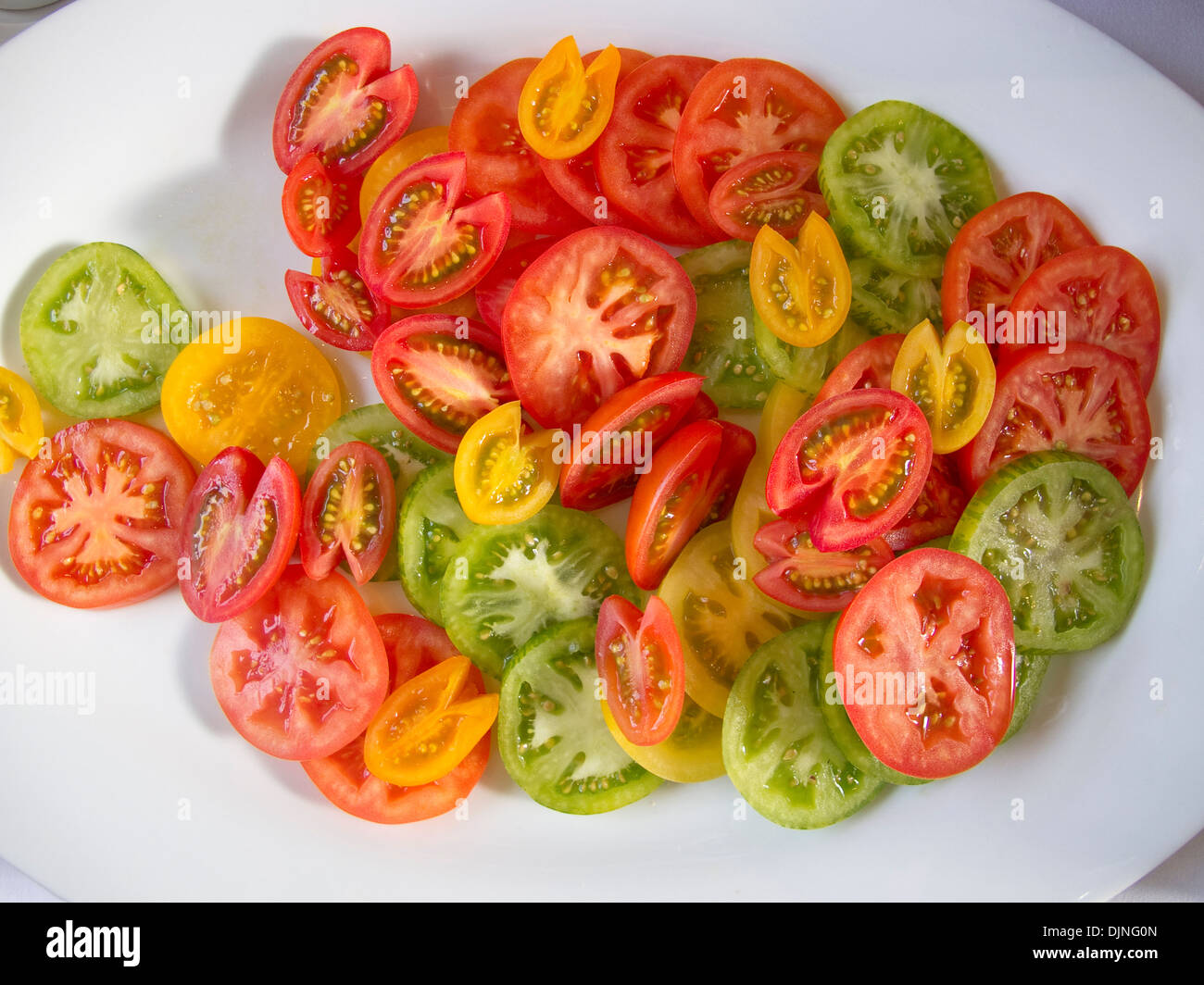 Verschiedene farbige Tomaten auf einem weißen Teller Stockfoto