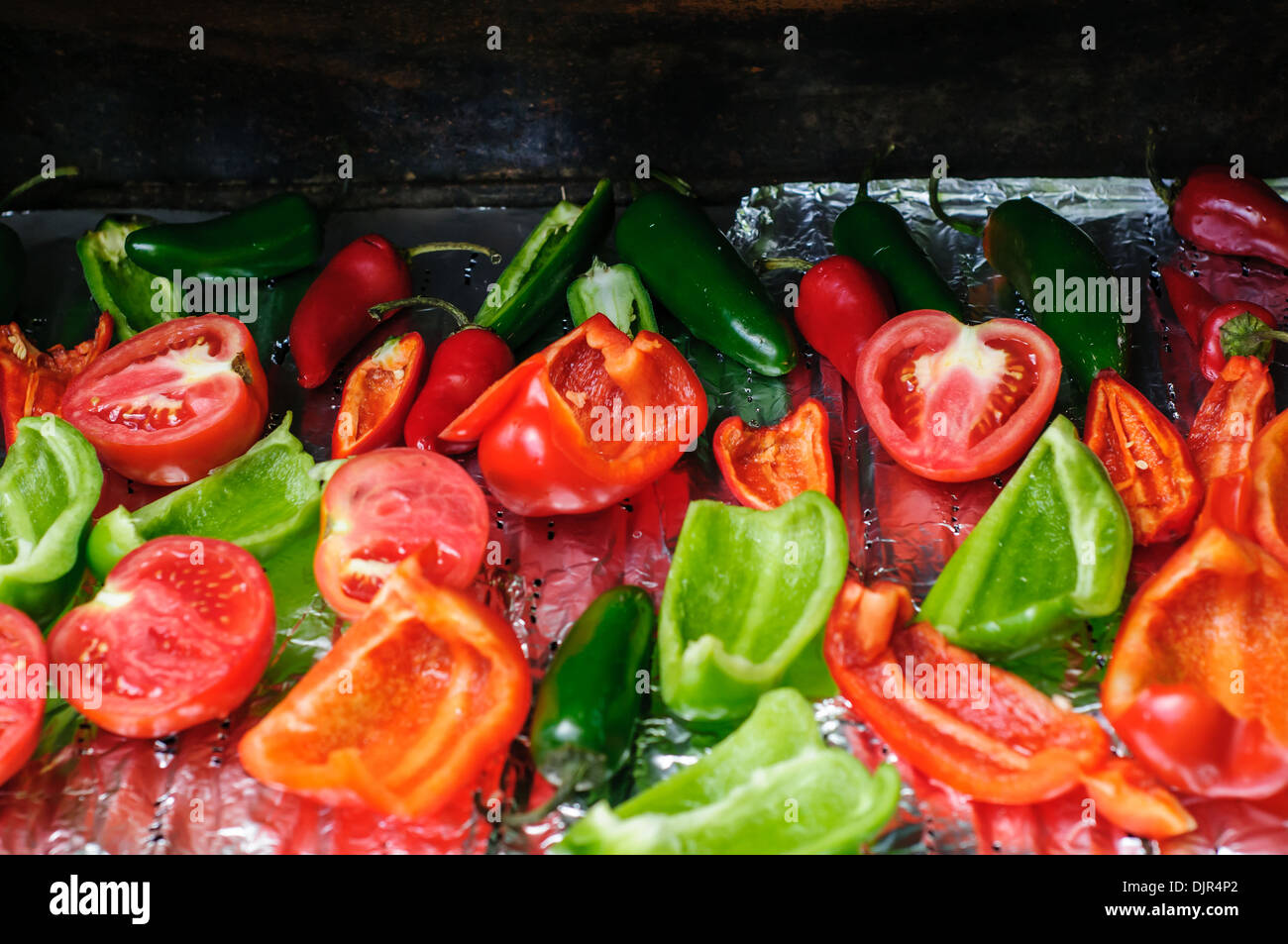 Tomaten, Jalapeños und grüne und rote Paprika auf dem Grill draußen Stockfoto
