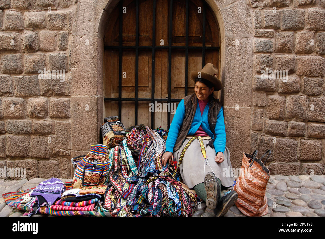 Quechua-Frau verkaufen lokale Gürtel und Teppiche in Loreto Straße, Cuzco, Peru. Stockfoto