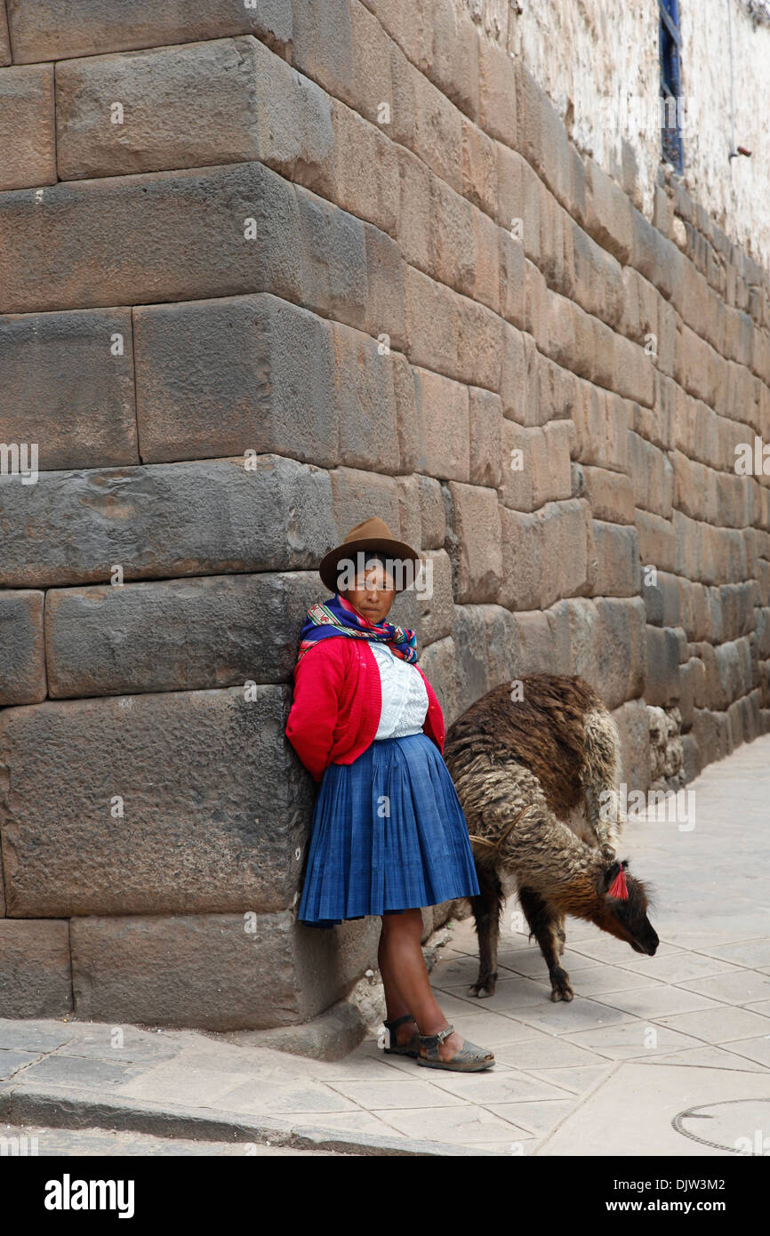 Quechua-Frau mit Lama entlang einer Inka-Wand in San Blas Nachbarschaft, Cuzco, Peru. Stockfoto