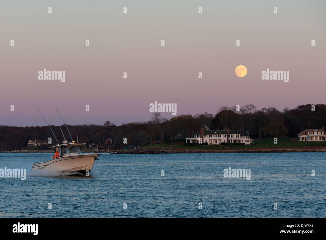 Ein Boot Geschwindigkeiten über Dering Hafen auf Shelter Island bei Vollmond Herbst Abend in Long Island, New York State Stockfoto