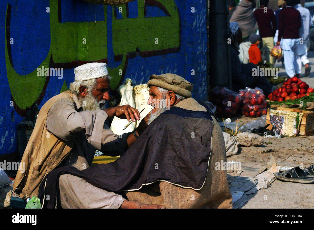 Peshawar, Pakistan. 1. Dezember 2013.  Eine Straße Barbier gibt Rasur mit einem Kunden während der Welt-Aids-Tag in Nordwest-Pakistan Peshawar, 1. Dezember 2013. Die internationale Welt-AIDS-Tag am 1. Dezember fällt widmet sich das Bewusstsein für AIDS-Pandemie durch die Ausbreitung der HIV-Infektion verursacht. Bildnachweis: Xinhua/Alamy Live-Nachrichten Stockfoto