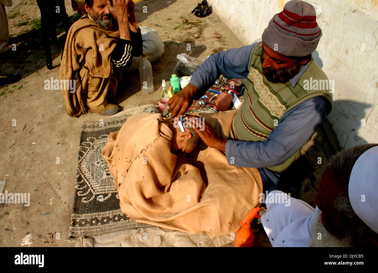 Peshawar, Pakistan. 1. Dezember 2013.  Eine Straße Barbier verleiht Haarschnitt eines Kindes während der Welt-Aids-Tag in Nordwest-Pakistan Peshawar, 1. Dezember 2013. Die internationale Welt-AIDS-Tag am 1. Dezember fällt widmet sich das Bewusstsein für AIDS-Pandemie durch die Ausbreitung der HIV-Infektion verursacht. Bildnachweis: Xinhua/Alamy Live-Nachrichten Stockfoto