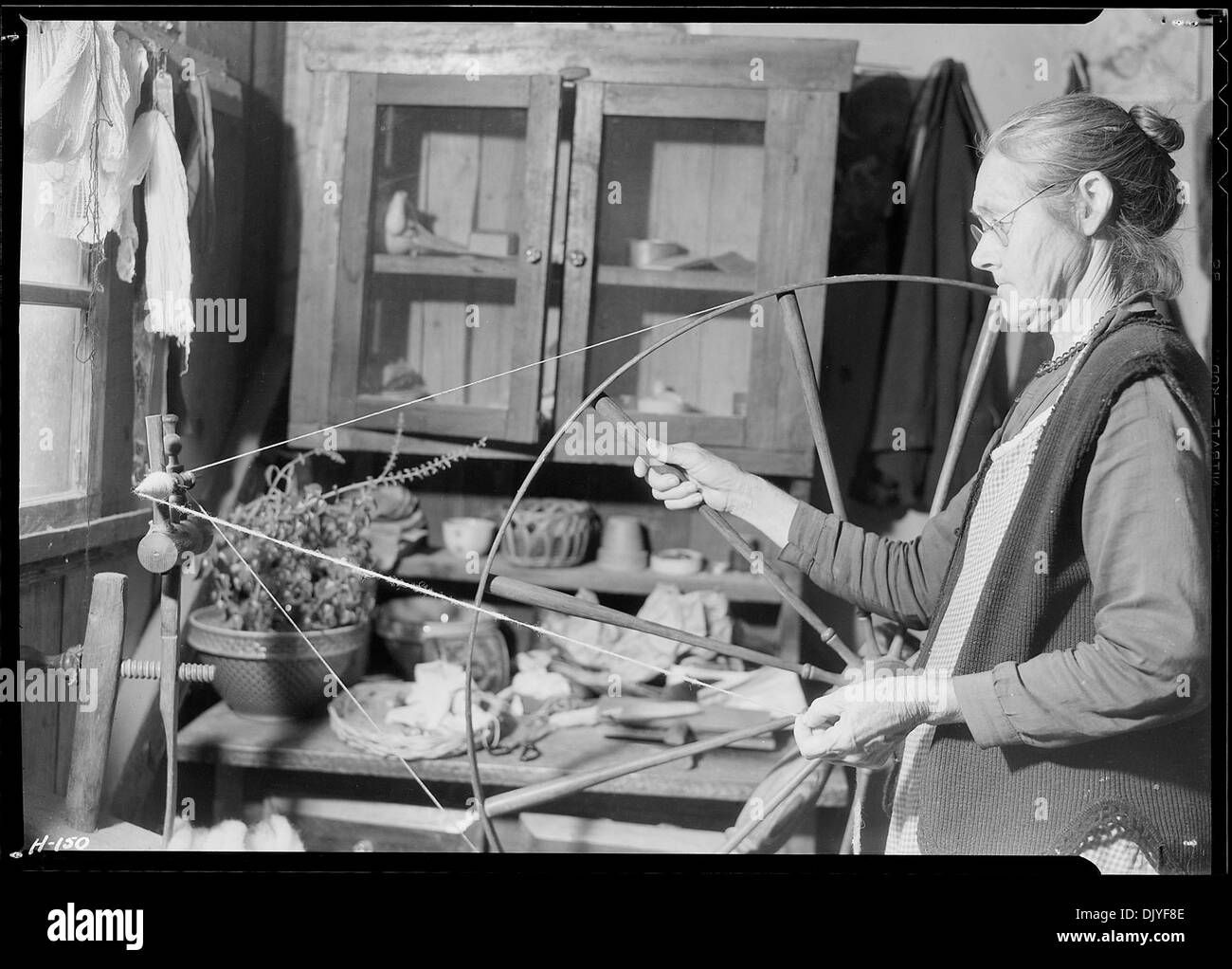 Dieses Bild zeigt Mrs. James Watson, die Wollgarn in ihrer Hütte in der Nähe von Gatlinburg, Tennessee spinnt und dabei traditionelle Handwerkskunst im frühen amerikanischen Siedlerleben hervorhebt. Stockfoto