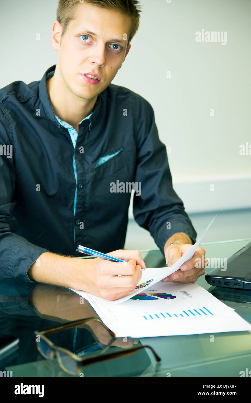 Jungunternehmer am Tisch sitzen und arbeiten mit Diagrammen Stockfoto