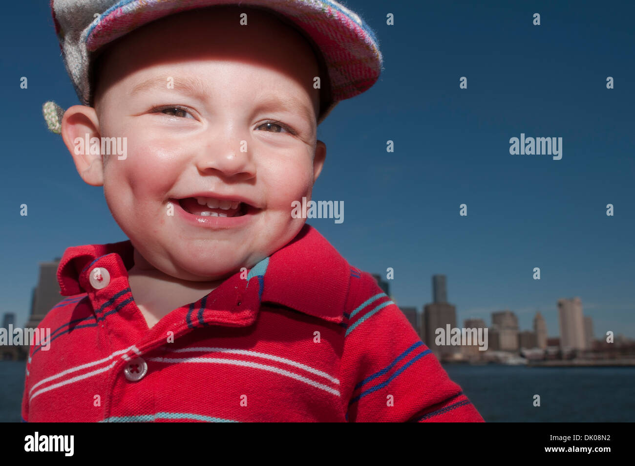 Ein 14 Monate altes Herr kaukasischen männliche Kleinkind stehen vor der Skyline von NYC im Brooklyn Bridge Park befindet sich in Brooklyn, New York. Stockfoto