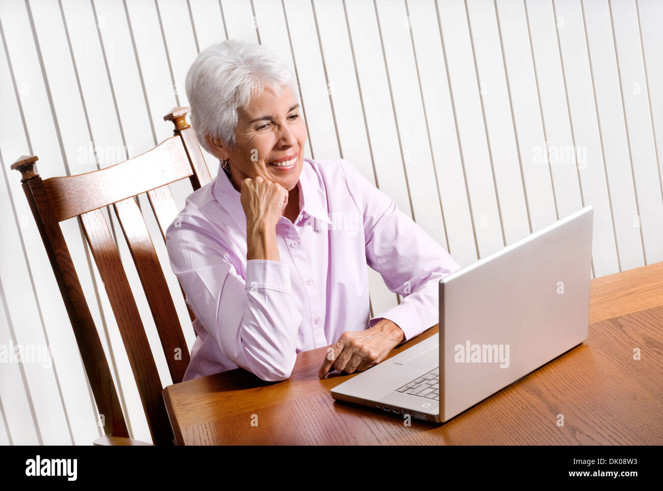Eine 65 Jahre alte Herr kaukasischen Frau arbeiten auf einem Computer in ihrem Wohnzimmer. Stockfoto