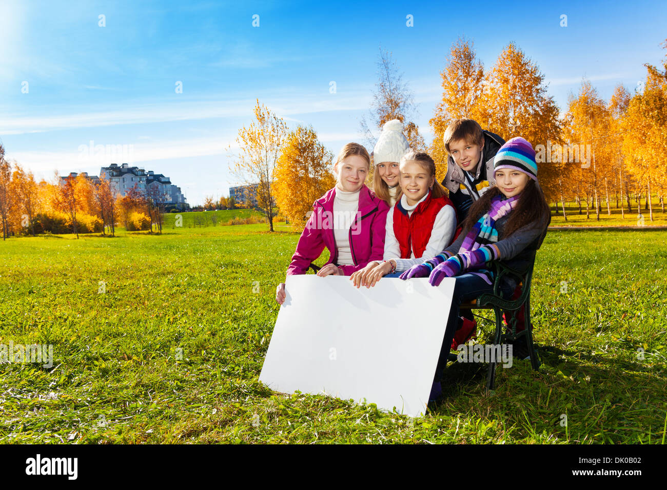 Gruppe von glücklich lächelnde Teen schulpflichtige Kinder sitzen auf der Bank im Park mit