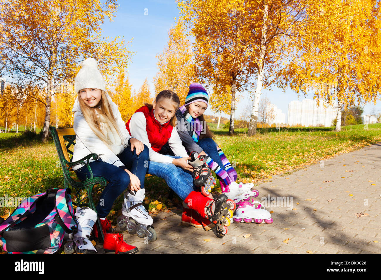Drei glückliche Mädchen setzen auf Rollerblades sitzen im park Stockfoto