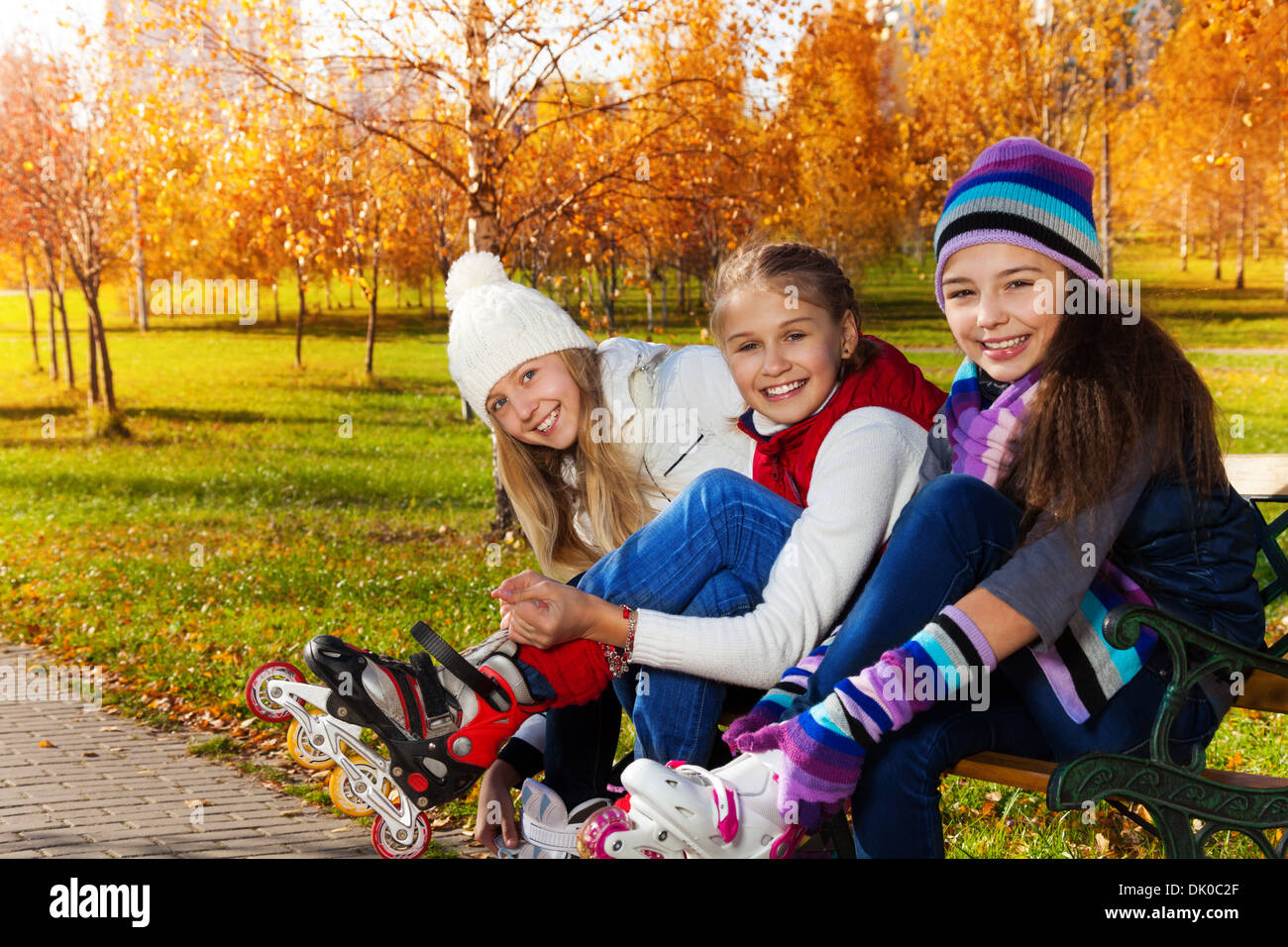 Enge Porträt von drei glückliche Mädchen setzen auf Rollerblades sitzen im park Stockfoto