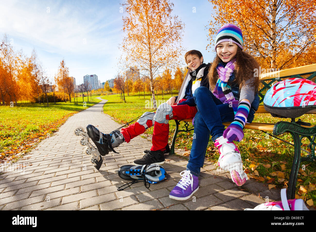 10 und 11 Jahre alt paar Schulkinder, junge ein Mädchen Rollschuhe in warme Herbst Kleidung anziehen Stockfoto
