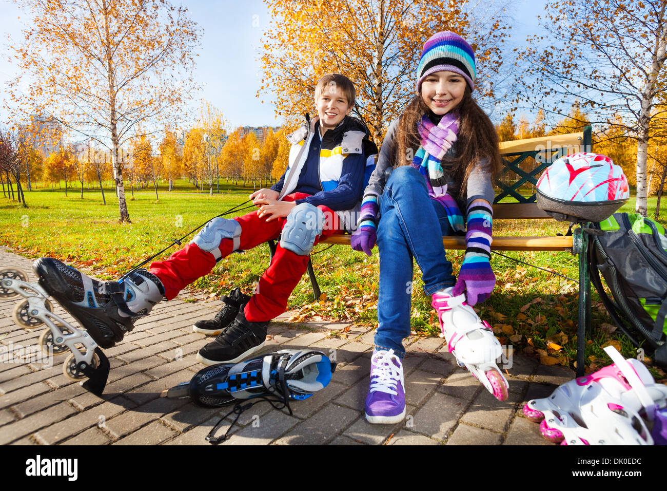10 und 11 Jahre alte Paar Schule Kinder, Junge ein Mädchen setzen auf Rolle Blätter in warmen Herbst Kleidung im Park schießen aus niedrigen Winkel Stockfoto