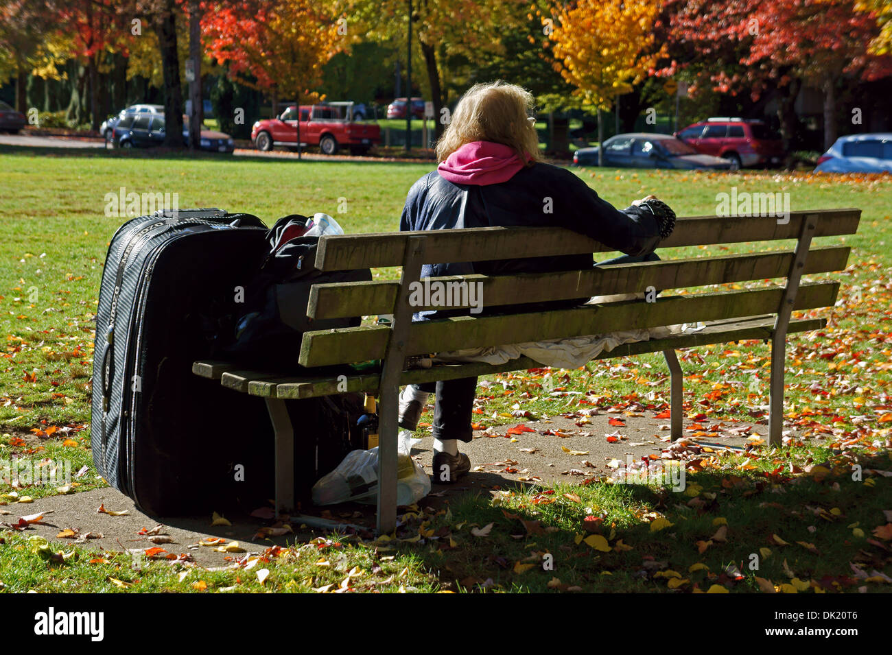 Obdachlose ältere Frau auf einer Parkbank mit ihren Habseligkeiten, Vancouver, BC, Kanada Stockfoto