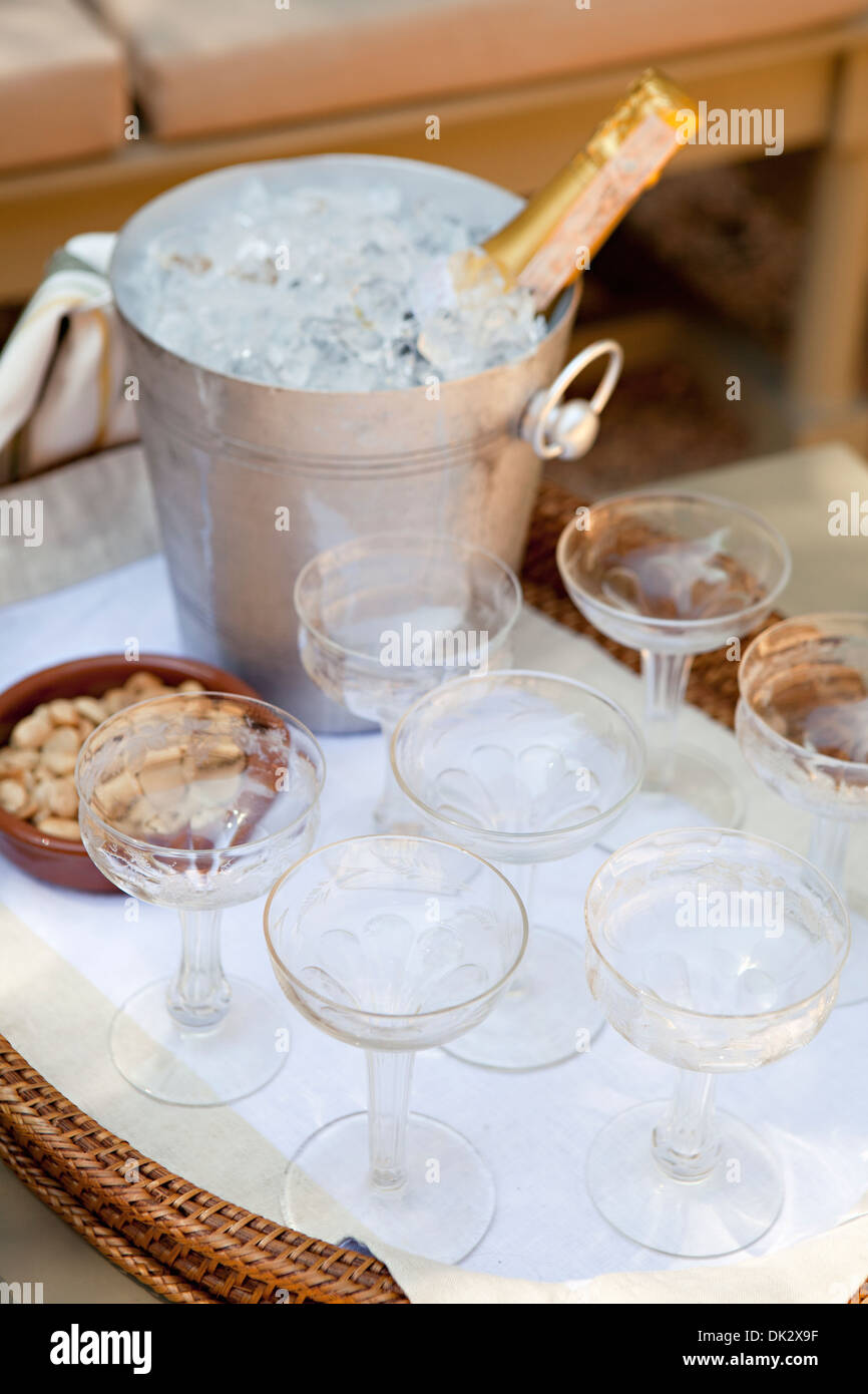 Flasche Champagner Kühlung in Silber Eiskübel auf Tablett mit Sektgläsern und Marcona Mandeln auf sonnigen Terrasse hoch Winkel vie Stockfoto