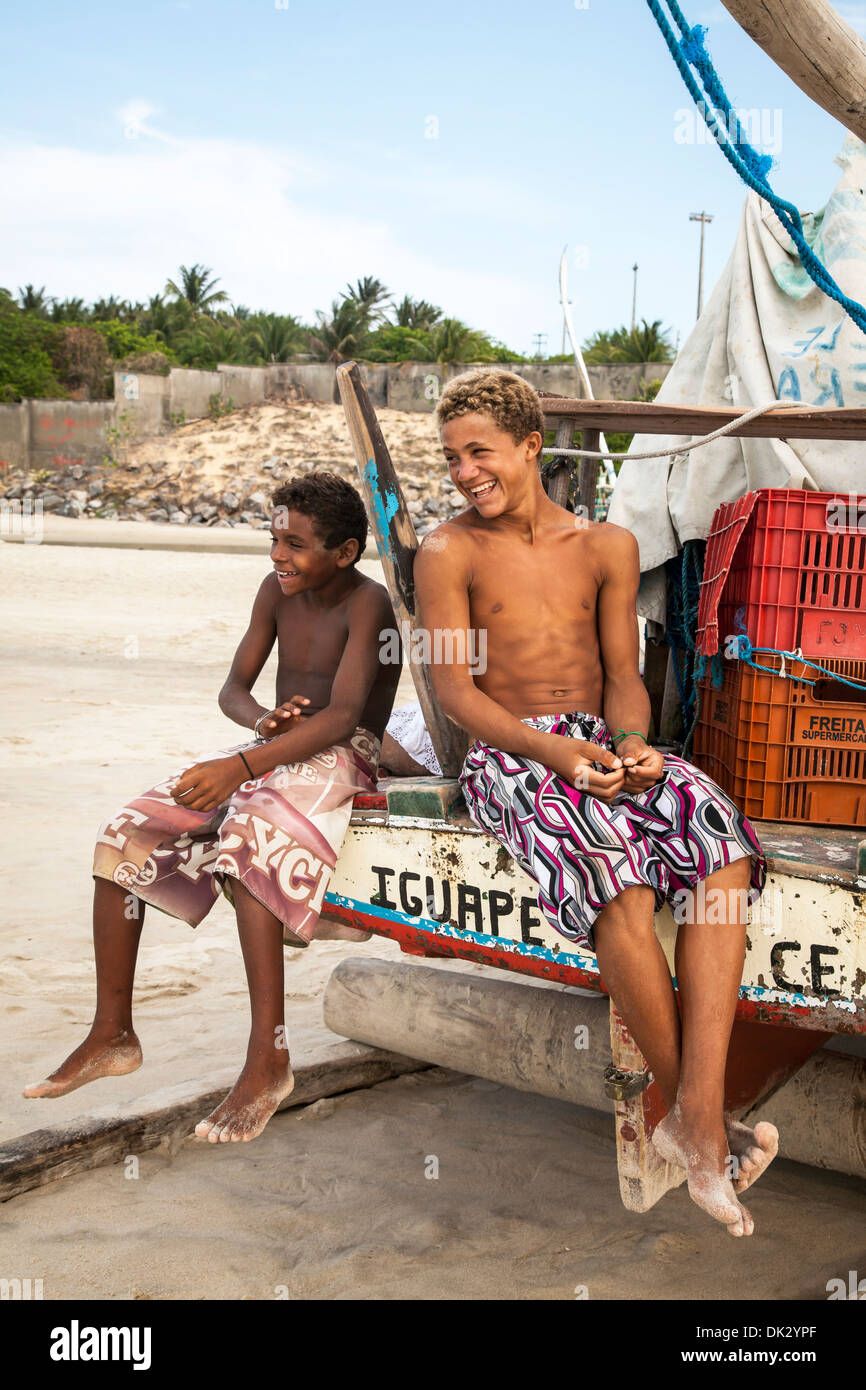 Lokalen jungen sitzen auf einer Jangada Boot, Iguape, Fortaleza Fischerviertel, Brasilien. Stockfoto