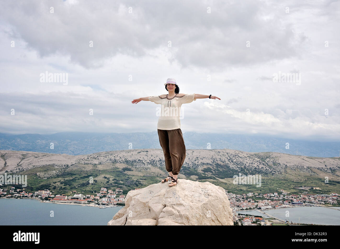 Porträt des Lächelns Mitte Erwachsene Frau mit ausgestreckten Armen auf Felsen, Insel Pag, Kroatien, Europa Stockfoto