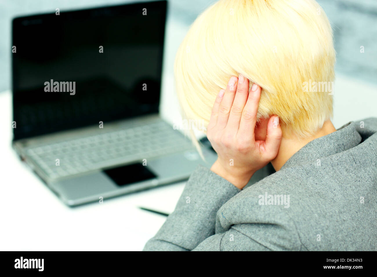 Junge Geschäftsfrau mit Kopfschmerzen an ihrem Arbeitsplatz im Büro Stockfoto